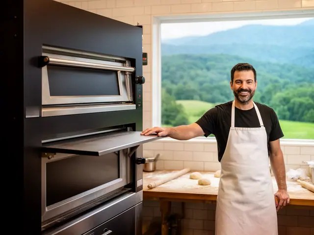 Smiling baker in a white apron resting a hand on the open door of a black deck oven